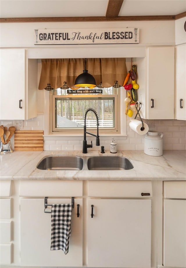 kitchen featuring plenty of natural light, a sink, white cabinetry, and tasteful backsplash