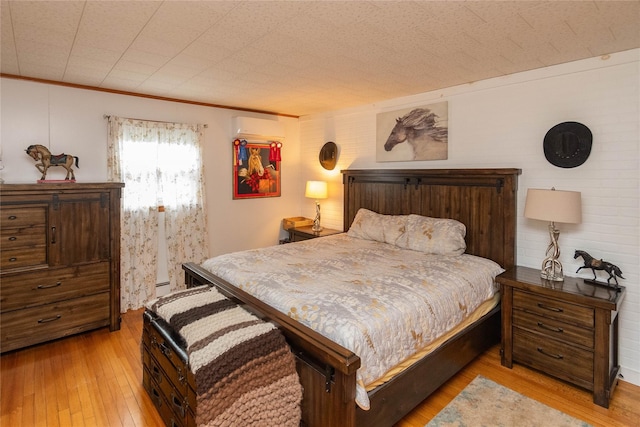 bedroom with a wall mounted air conditioner and wood-type flooring