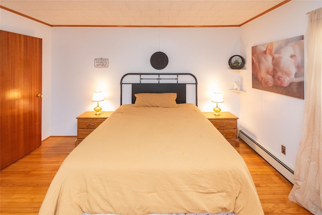 bedroom featuring baseboard heating, crown molding, and light wood finished floors
