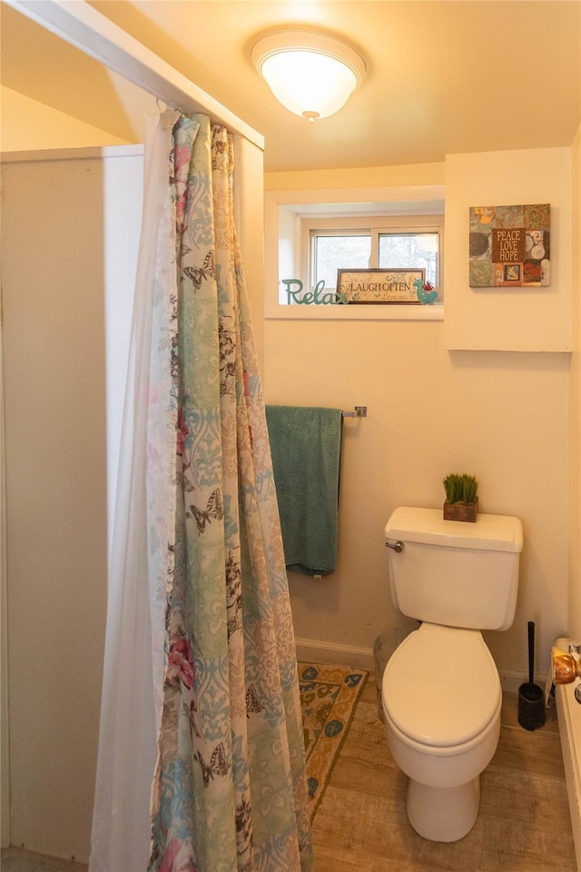 bathroom with curtained shower, toilet, and baseboards