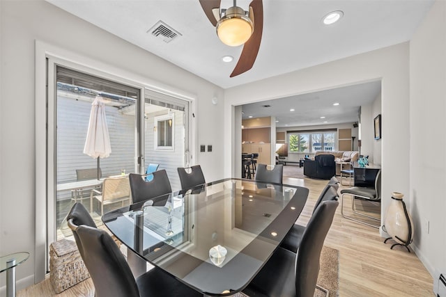 dining area with a baseboard radiator, wood finished floors, ceiling fan, baseboards, and visible vents