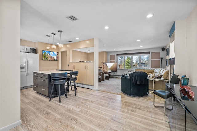 living room featuring baseboard heating, recessed lighting, visible vents, and light wood-style flooring