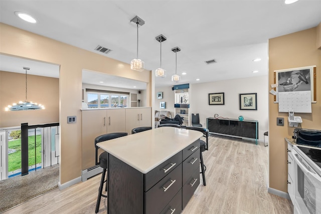 kitchen featuring baseboard heating, a kitchen breakfast bar, electric stove, light wood finished floors, and visible vents