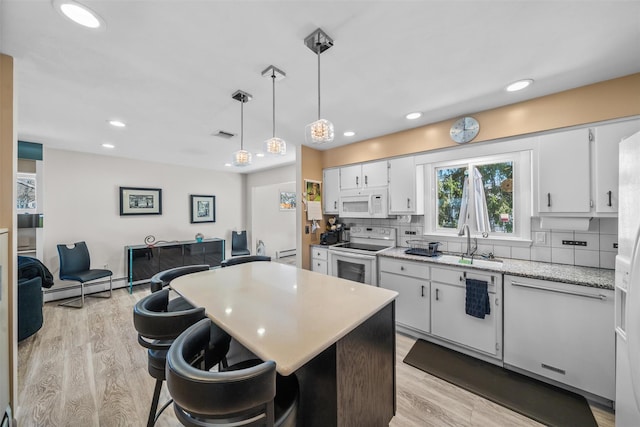 kitchen with light wood-style floors, tasteful backsplash, white cabinetry, and white appliances