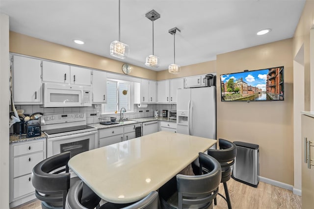 kitchen featuring tasteful backsplash, light wood-type flooring, baseboards, recessed lighting, and white appliances