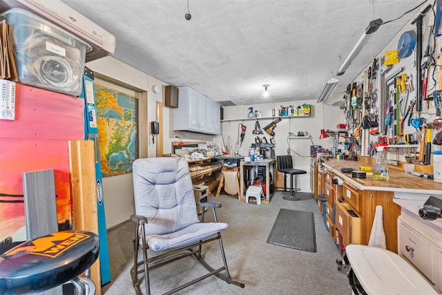 miscellaneous room with a textured ceiling, carpet, and a workshop area