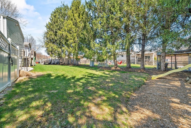 view of yard with a wooden deck, stairs, and fence