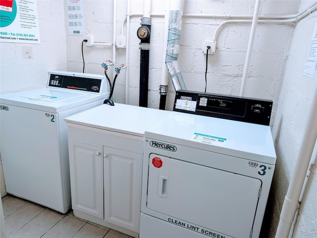 clothes washing area featuring cabinet space, light tile patterned floors, and separate washer and dryer