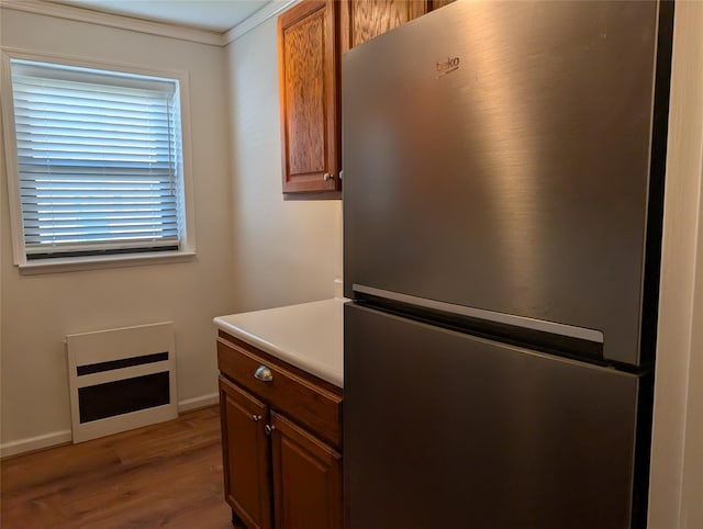kitchen featuring light countertops, wood finished floors, freestanding refrigerator, and brown cabinetry