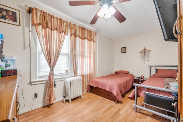 bedroom with radiator, baseboards, a ceiling fan, and light wood finished floors