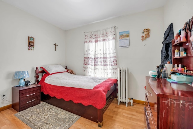 bedroom with baseboards, radiator heating unit, and light wood-style flooring