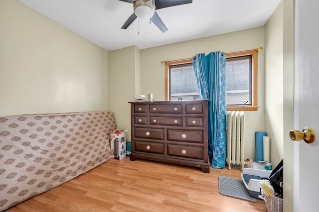 bedroom with radiator, light wood finished floors, and ceiling fan