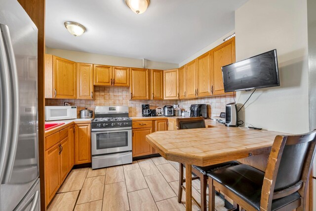 kitchen with backsplash, light countertops, and appliances with stainless steel finishes