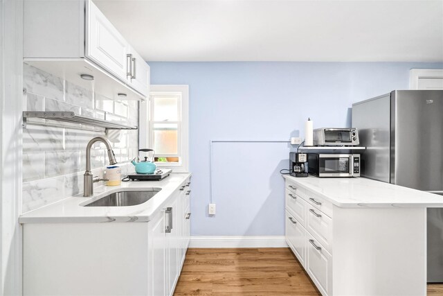 kitchen featuring a toaster, stainless steel appliances, light wood finished floors, and a sink