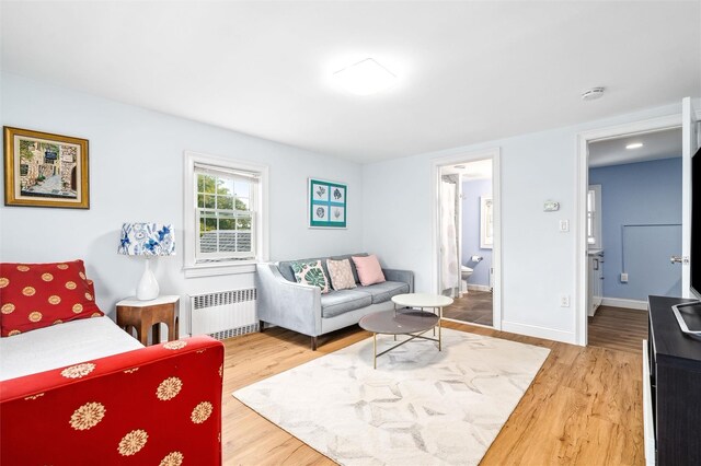 bedroom with baseboards, radiator heating unit, wood finished floors, and ensuite bathroom