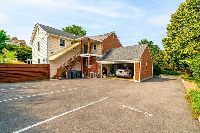 view of front of property featuring brick siding, stairs, uncovered parking, and fence