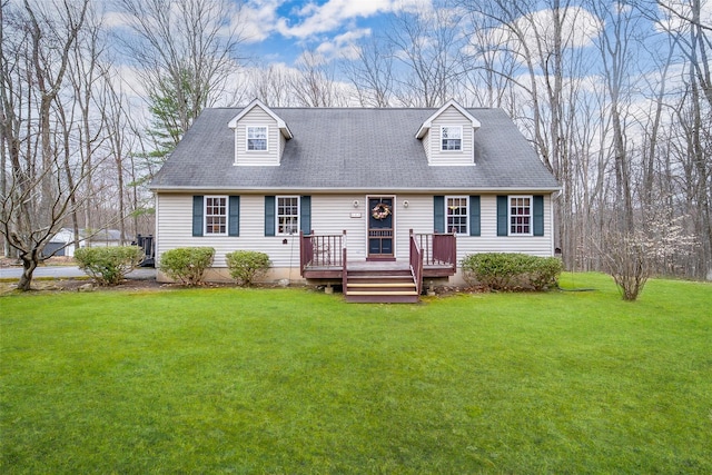cape cod house featuring roof with shingles, a front yard, and a deck