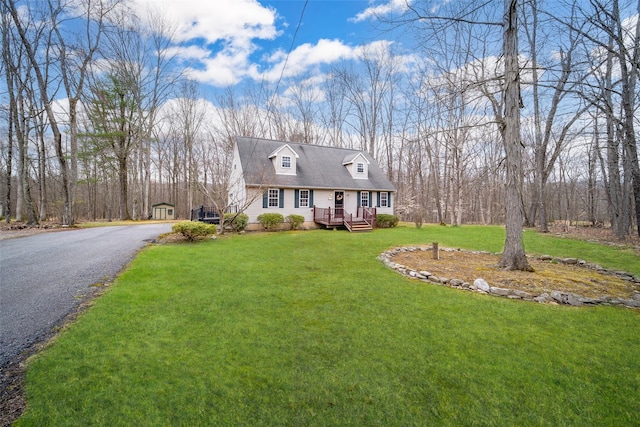 new england style home featuring a wooden deck, driveway, and a front yard