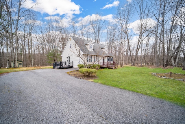 view of side of home featuring an outdoor structure, a lawn, driveway, and a deck