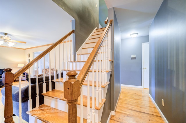 stairway with wood finished floors, a ceiling fan, and baseboards