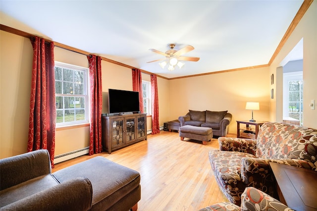 living room with crown molding, light wood finished floors, baseboard heating, and a ceiling fan