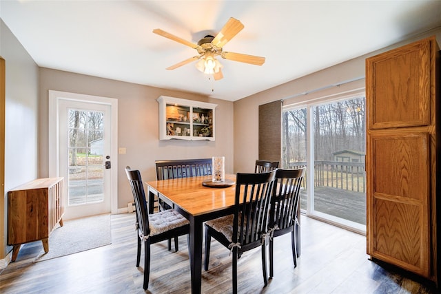 dining space with light wood finished floors, baseboards, and a ceiling fan