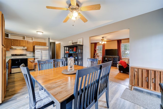 dining area with a ceiling fan and light wood-style floors