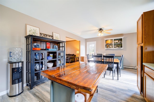 dining room with light wood-type flooring, baseboard heating, baseboards, and ceiling fan