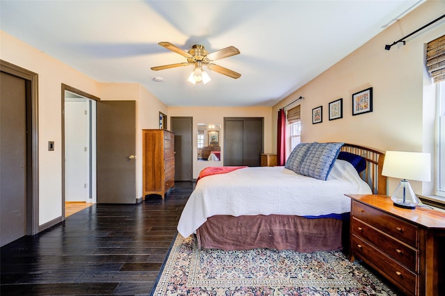bedroom featuring baseboards, two closets, a ceiling fan, and hardwood / wood-style flooring