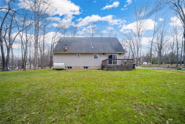 rear view of house featuring a wooden deck, heating fuel, and a lawn