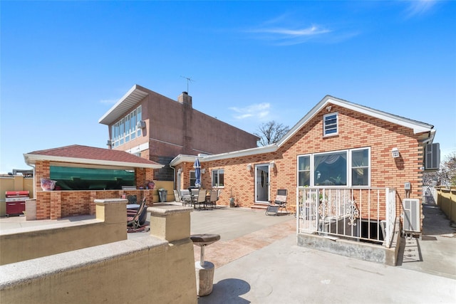 rear view of property featuring brick siding, a patio area, and central AC unit
