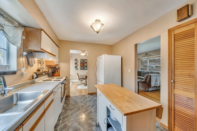 kitchen featuring a ceiling fan, a sink, wood counters, white appliances, and white cabinets
