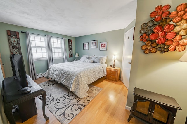 bedroom featuring a baseboard heating unit and wood finished floors