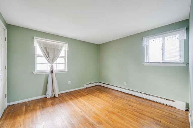 unfurnished room with baseboards, hardwood / wood-style floors, and baseboard heating
