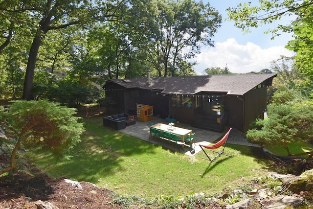 rear view of property featuring a lawn, a patio area, and a shingled roof