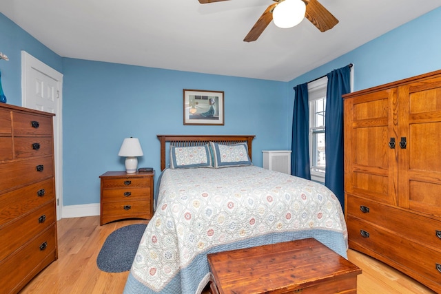 bedroom with light wood finished floors, baseboards, and ceiling fan
