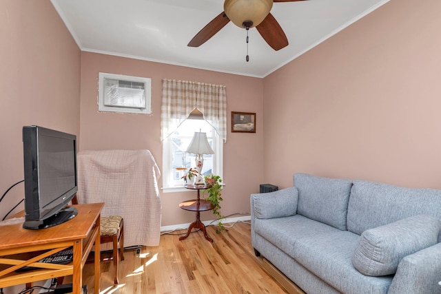 living room with a ceiling fan, baseboards, ornamental molding, and light wood-type flooring