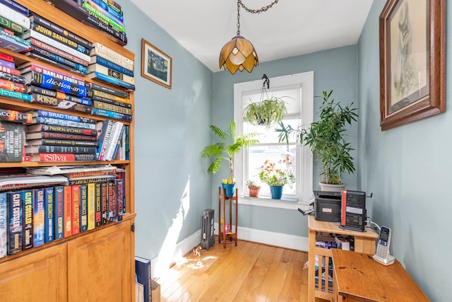 sitting room with radiator heating unit, light wood finished floors, and baseboards