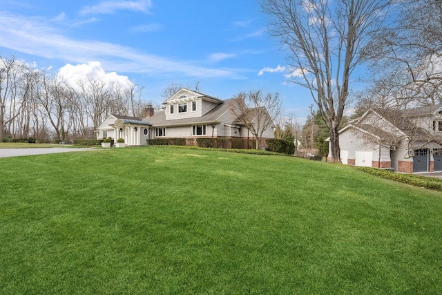 99 Wheatley Rd, Old Westbury, NY 11568 - view of front of house featuring a chimney, a front lawn, driveway, and a garage