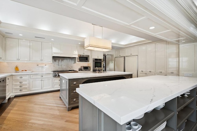99 Wheatley Rd, Old Westbury, NY 11568 - kitchen with tasteful backsplash, light wood-style floors, a kitchen island with sink, stainless steel appliances, and light stone countertops