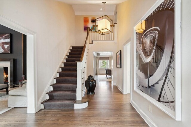 99 Wheatley Rd, Old Westbury, NY 11568 - entrance foyer with stairs, a towering ceiling, dark wood-type flooring, and baseboards