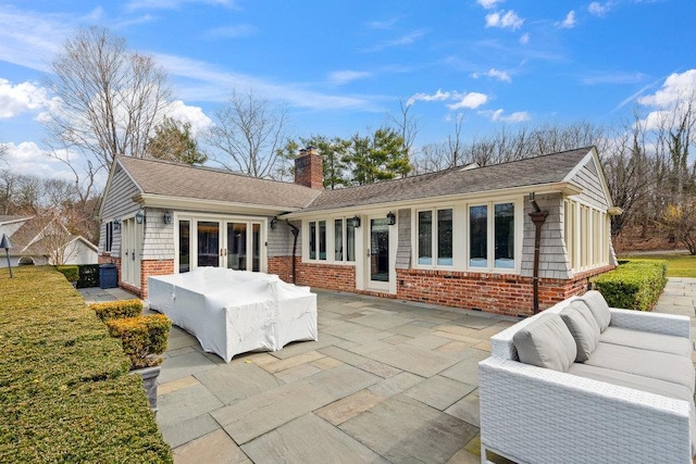 99 Wheatley Rd, Old Westbury, NY 11568 - rear view of property with roof with shingles, a chimney, brick siding, outdoor lounge area, and a patio area