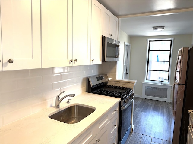 kitchen featuring a sink, radiator, appliances with stainless steel finishes, and backsplash