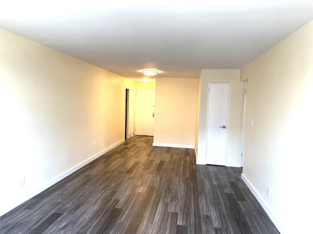 unfurnished room with baseboards and dark wood-style floors