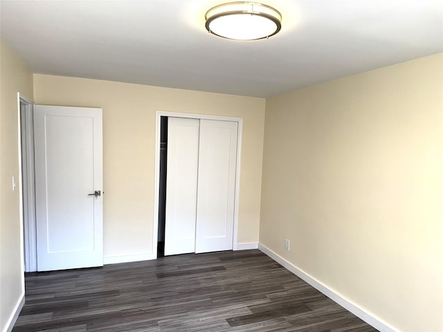 unfurnished bedroom featuring baseboards, a closet, and dark wood-style flooring