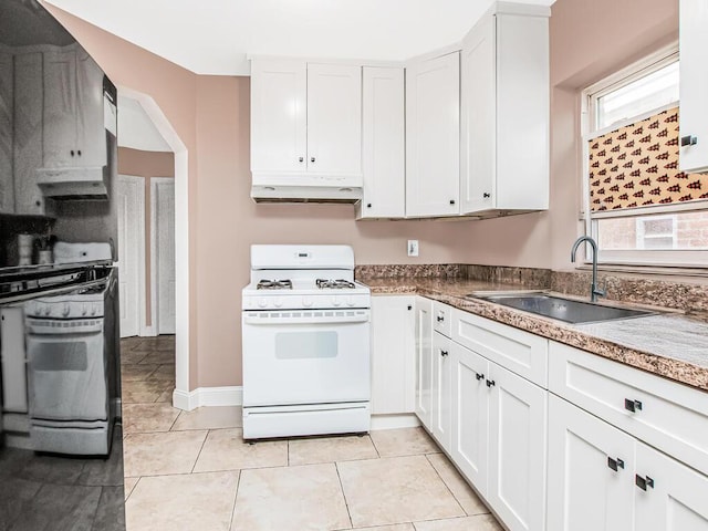kitchen with a sink, white cabinets, white gas stove, and under cabinet range hood