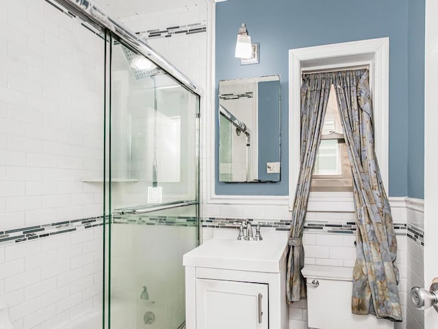 bathroom featuring vanity, shower / bath combination with glass door, and tile walls