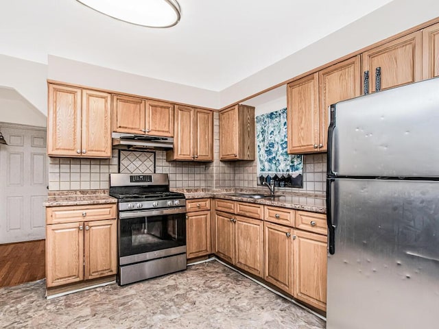 kitchen featuring backsplash, a sink, appliances with stainless steel finishes, and under cabinet range hood