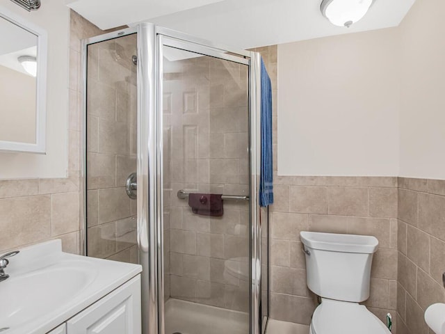bathroom featuring vanity, tile walls, a shower stall, and toilet