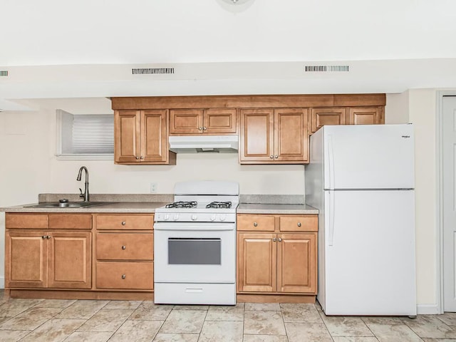 kitchen with visible vents, a sink, brown cabinets, and white appliances